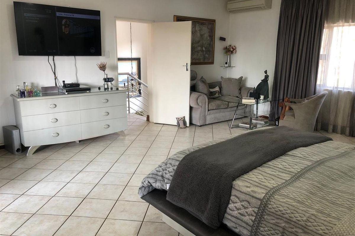 Spacious bedroom featuring tiled flooring and a wall-mounted air conditioning unit, offering a comfortable and functional living space.