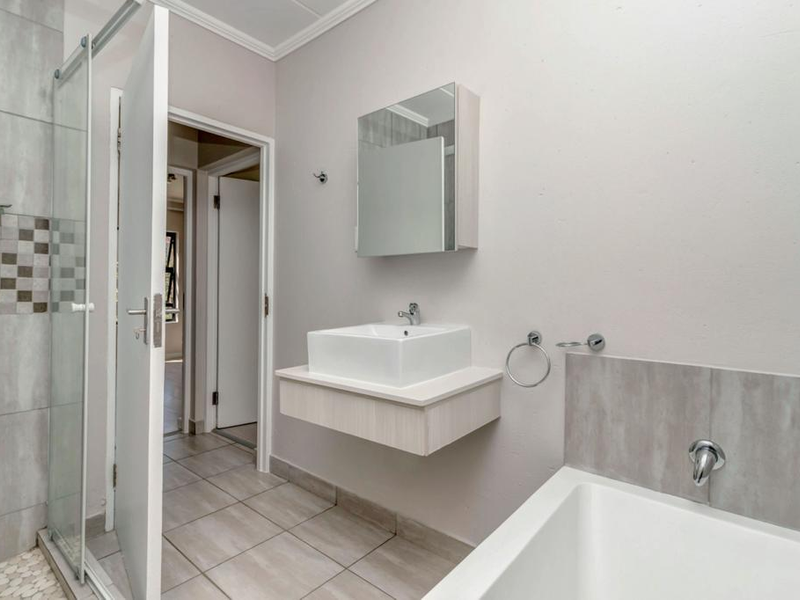 Modern bathroom featuring a wall-mounted vanity with vessel sink, a separate shower enclosure with tiled walls, and a bathtub.