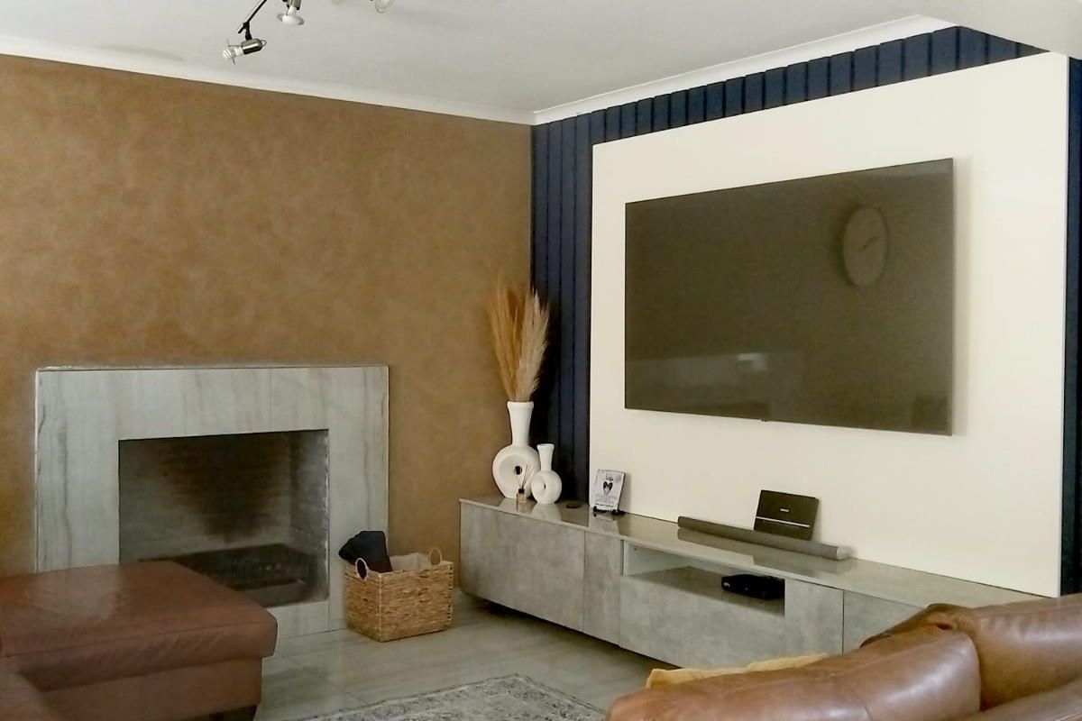 A comfortable living room featuring a built-in fireplace with a stone surround and a modern feature wall with integrated media cabinetry.