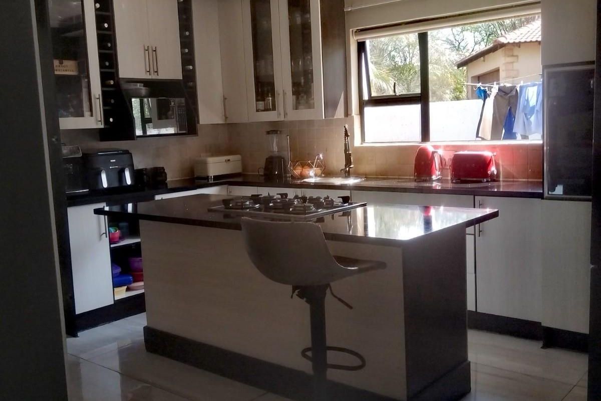 Modern kitchen featuring a central island with a built-in gas hob, sleek cabinetry, tiled flooring, and ample counter space.