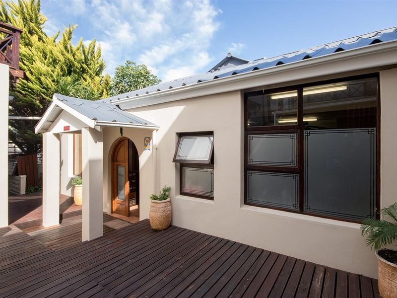 A well-maintained lodge exterior featuring a covered entrance, timber decking, and large windows with frosted glass detailing.