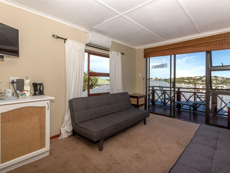 A comfortable living room featuring a wall-mounted air conditioning unit, sliding glass doors leading to a balcony, and views of the surrounding area.