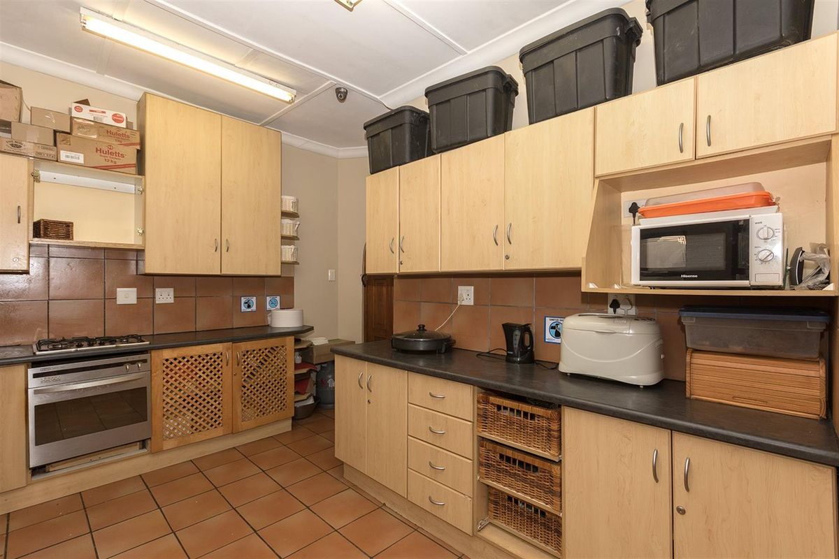 A functional kitchen featuring light wood cabinetry, dark countertops, a built-in oven with gas hob, and tiled flooring.