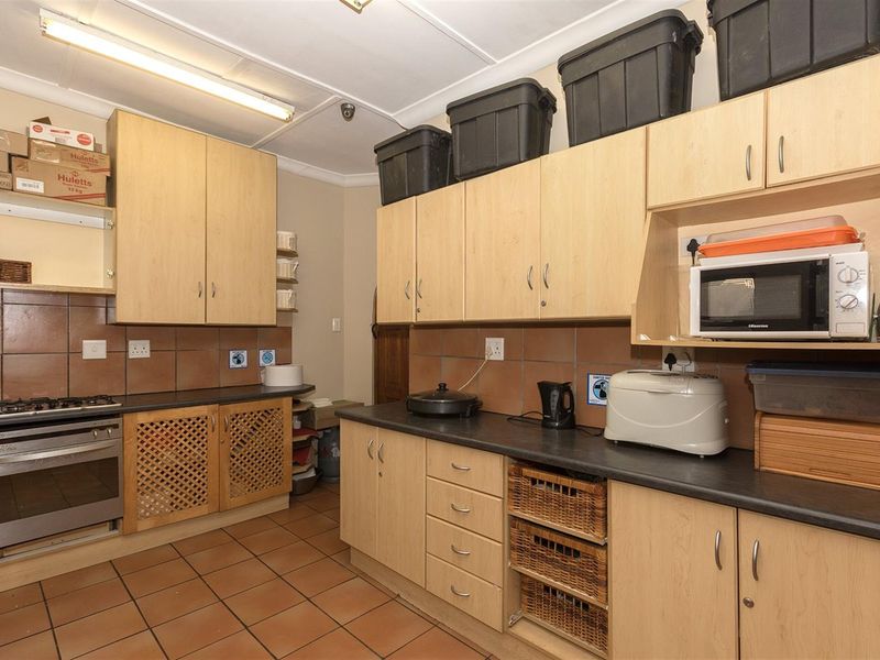 A functional kitchen featuring light wood cabinetry, dark countertops, a built-in oven with gas hob, and tiled flooring.