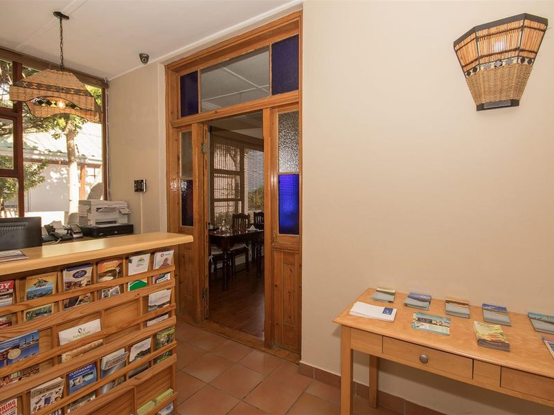 A lodge reception area featuring a built-in wooden service counter, tiled flooring, and a timber-framed doorway leading to an adjacent dining space.