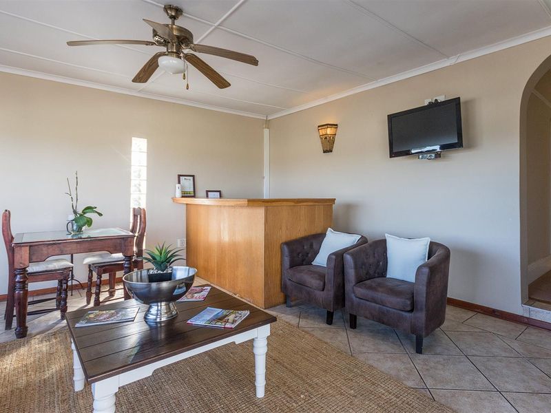 Open plan living area featuring a built-in wooden bar counter, tiled flooring, ceiling fan, and arched entryway leading to the hallway.