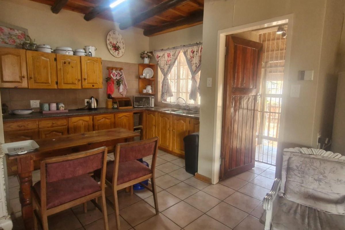 A rustic kitchen featuring wooden cabinetry, tiled flooring, and exposed timber ceiling beams, providing a warm and traditional atmosphere.