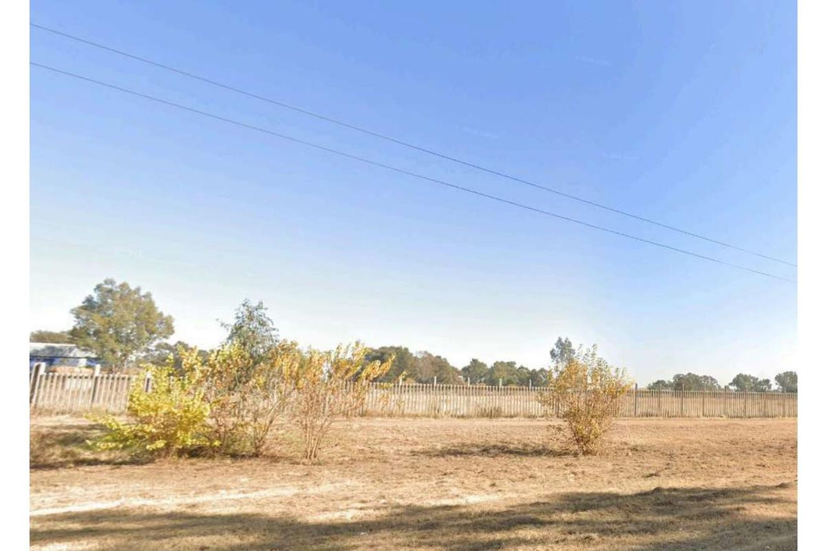 A view of the rear property boundary featuring perimeter fencing and open land.