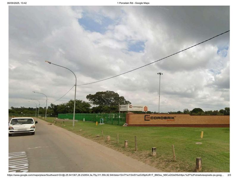 Street view of the industrial property entrance featuring a brick boundary wall, perimeter fencing, and signage.
