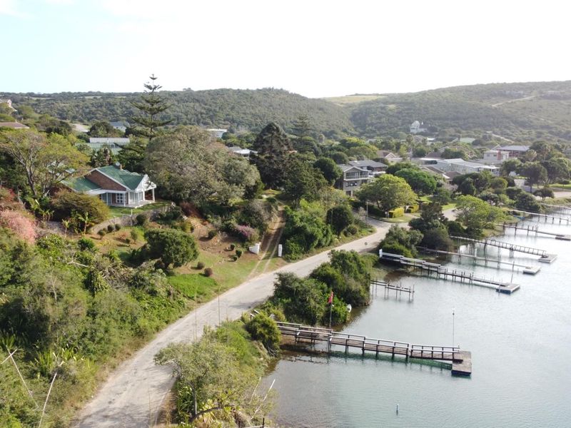 Aerial view of a residential property featuring a waterfront location with private jetties, lush greenery, and surrounding coastal landscape.