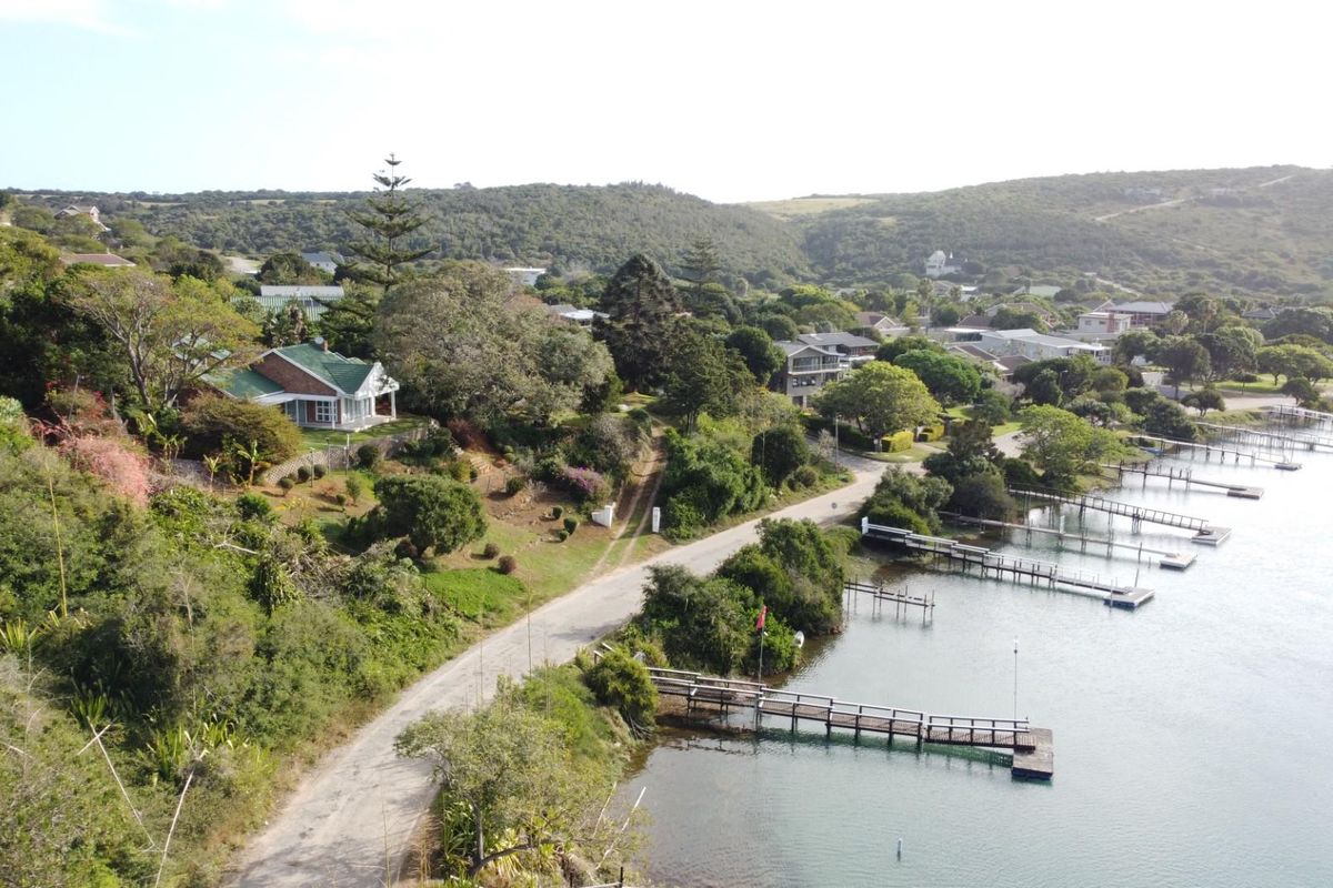 Aerial view of a residential property featuring a waterfront location with private jetties, lush greenery, and surrounding coastal landscape.
