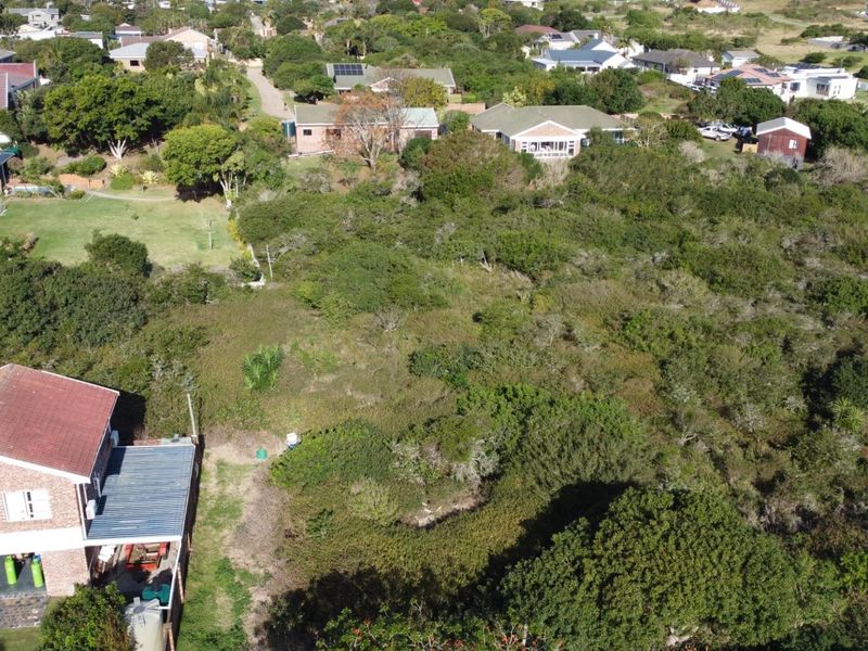 Aerial view of a vacant residential plot featuring dense natural vegetation and surrounding established neighborhood housing.