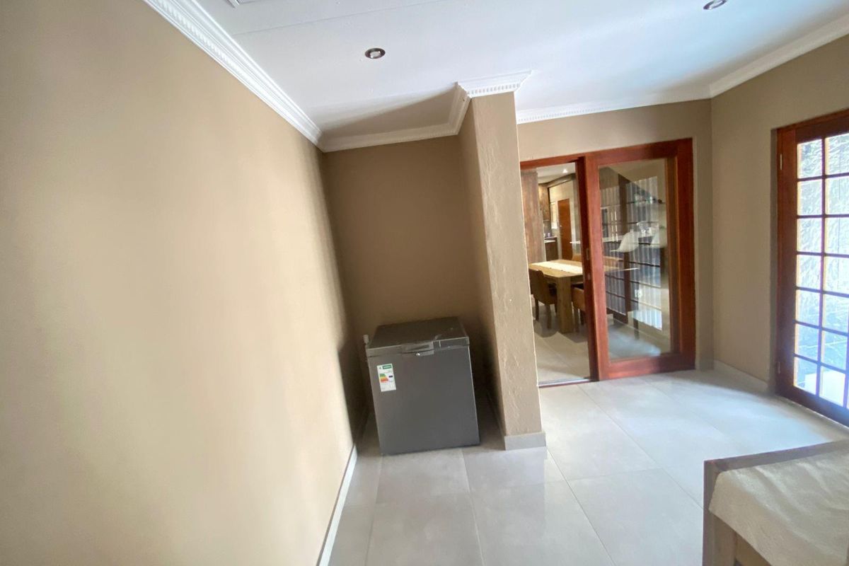 A tiled interior space featuring recessed ceiling lighting, crown molding, and sliding glass doors providing access to an adjacent dining area.