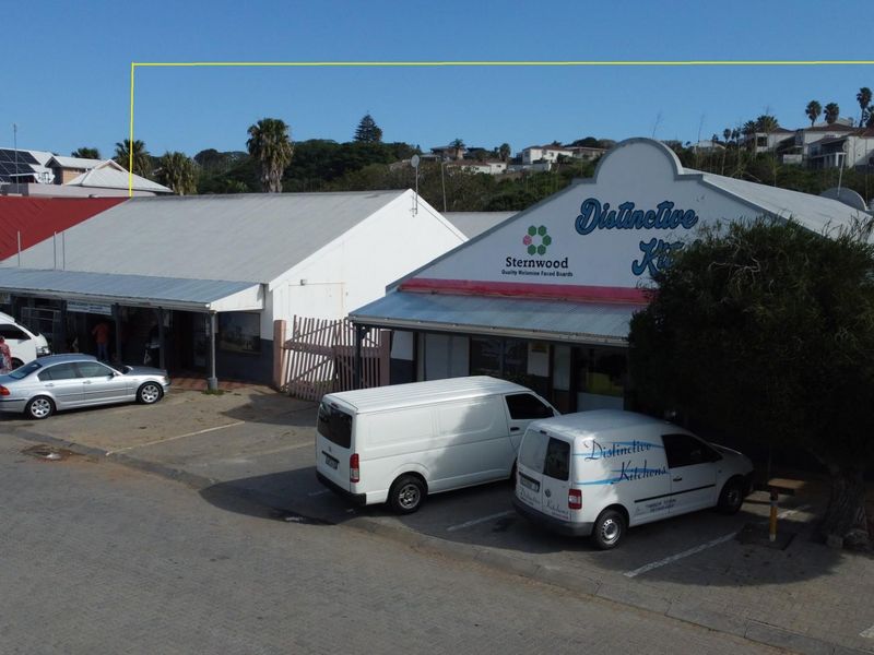 Aerial view of a commercial property complex featuring multiple storefronts with paved parking area and signage.