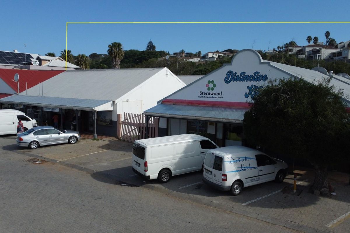 Aerial view of a commercial property complex featuring multiple storefronts with paved parking area and signage.