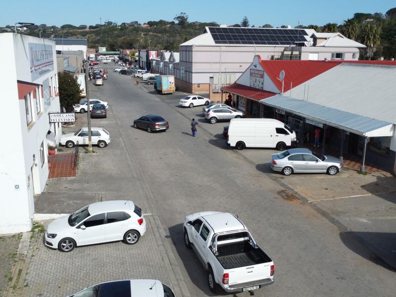 Aerial view of a commercial street featuring various retail storefronts, paved road access, and on-street parking facilities.