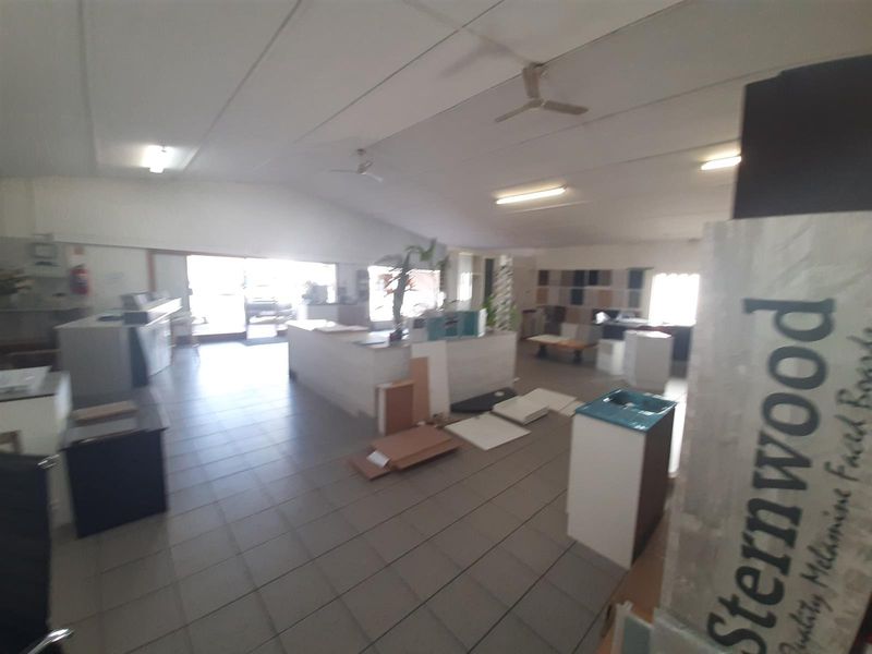 Spacious commercial showroom or office area featuring tiled flooring, ceiling fans, and integrated lighting, suitable for retail or professional workspace use.