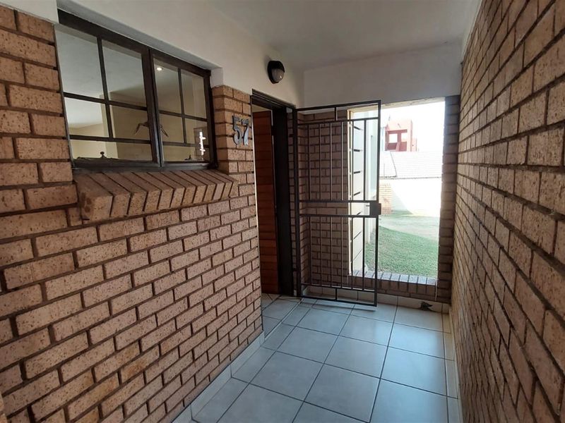 A private entrance area featuring exposed brick walls, tiled flooring, and a secure metal gate leading to the exterior.