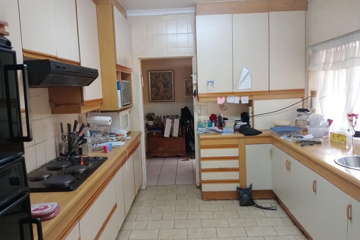 A functional kitchen featuring built-in cabinetry, a fitted hob, extractor fan, and tiled flooring, offering a practical layout for daily meal preparation.