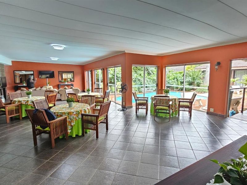 Spacious open-plan entertainment area featuring tiled flooring, large sliding glass doors, and direct access to the outdoor pool area.