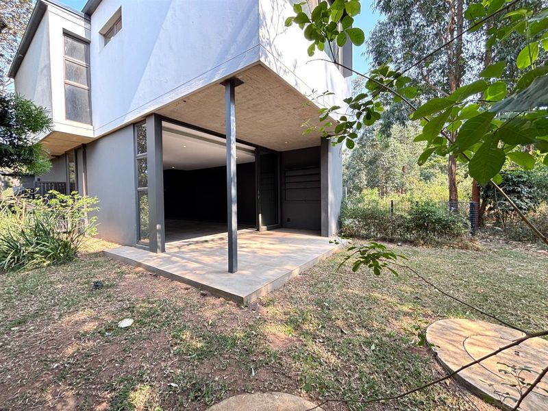 Rear view of the townhouse featuring a covered patio area with sliding glass doors leading into the living space and a private garden.