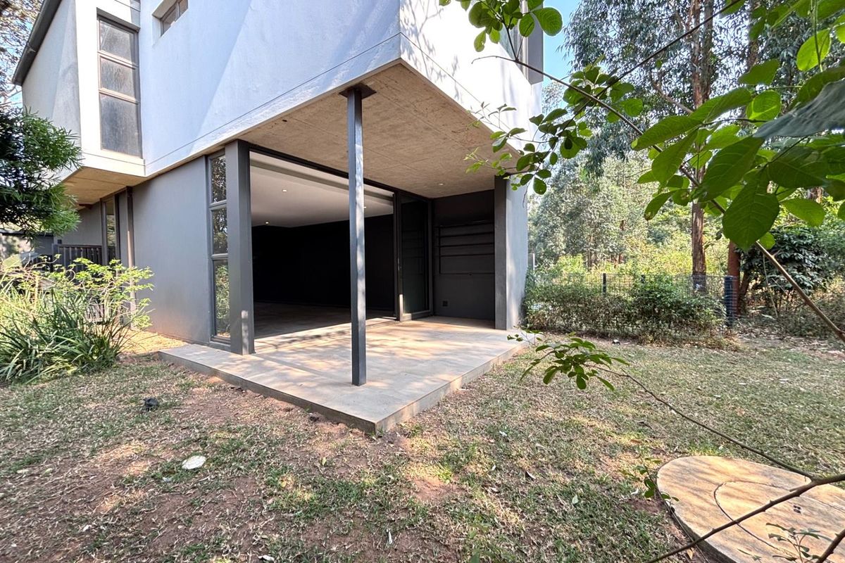 Rear view of the townhouse featuring a covered patio area with sliding glass doors leading into the living space and a private garden.