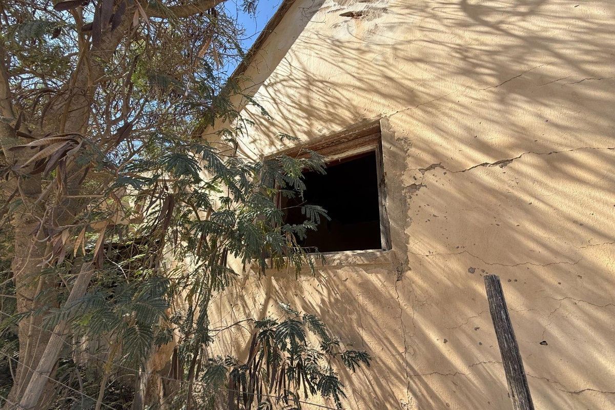 Exterior view of a property facade showing significant structural weathering, cracked plaster, and a missing window frame requiring major restoration.