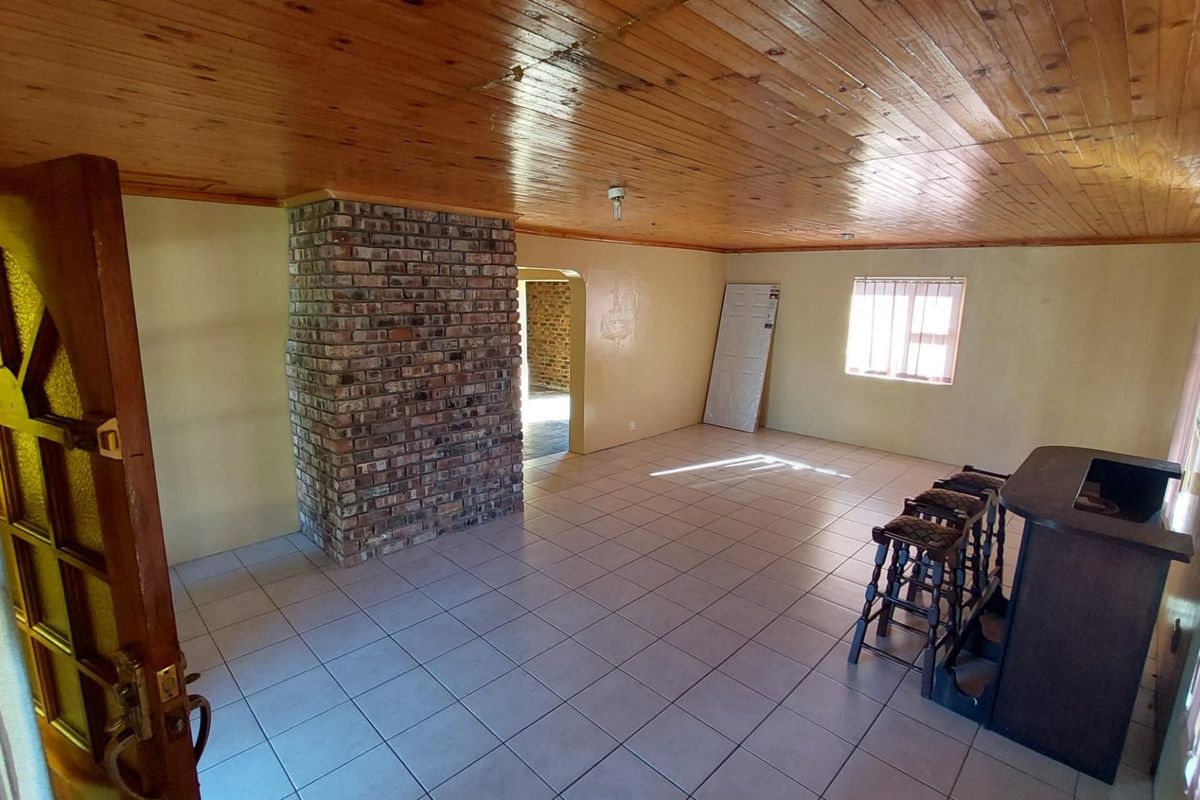 Spacious living area featuring a prominent brick fireplace, timber-clad ceiling, tiled flooring, and a built-in bar counter.