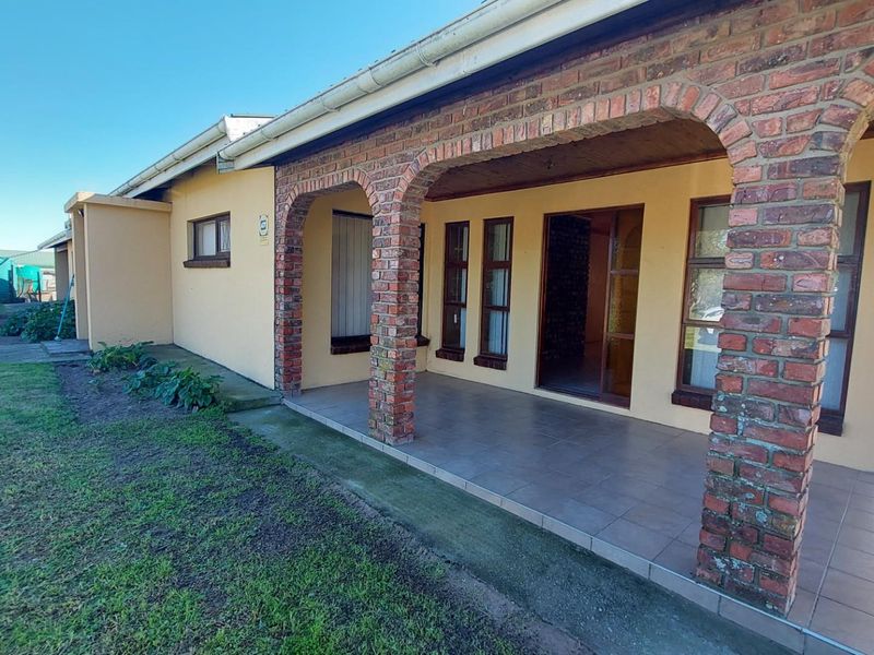 A covered patio area featuring rustic brick archways, tiled flooring, and a timber ceiling, providing direct access to the interior living space.