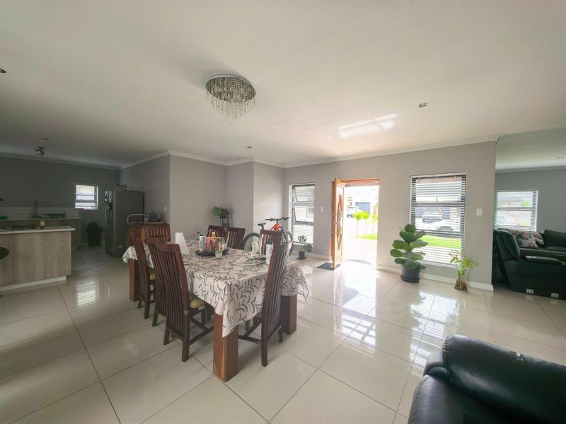 Spacious open-plan living and dining area featuring polished porcelain tiles, modern lighting, and seamless flow into the adjacent kitchen space.