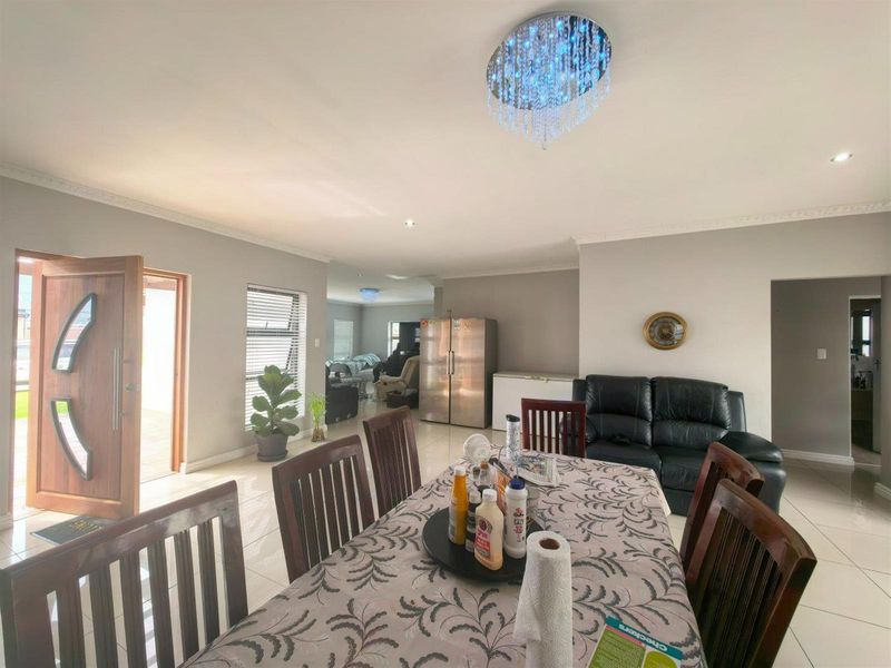 Spacious open-plan living and dining area featuring tiled floors, decorative cornicing, and modern lighting fixtures, providing a bright and versatile layout.