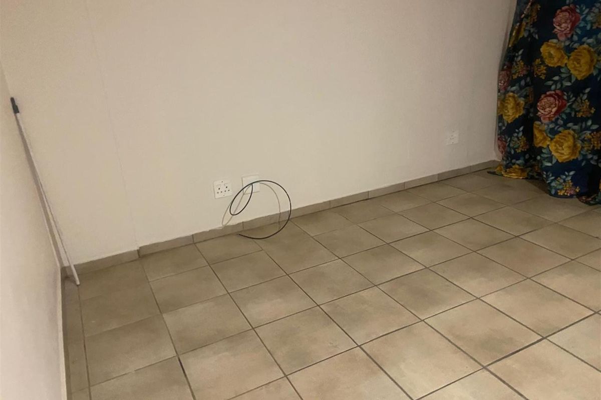 A sparsely furnished room featuring neutral floor tiles and exposed electrical wiring, offering a blank canvas for potential interior updates.