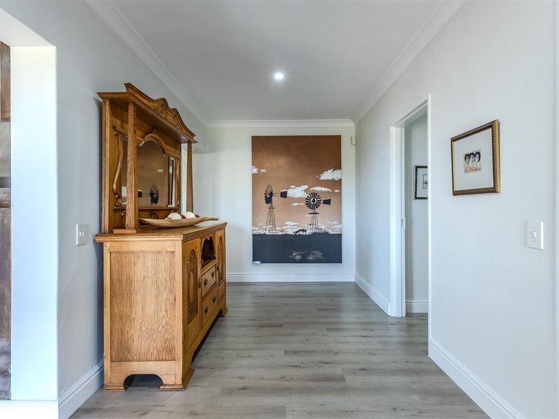 A bright and well-maintained hallway featuring modern laminate flooring, crisp white walls, and recessed downlighting, creating a clean and welcoming transition space.