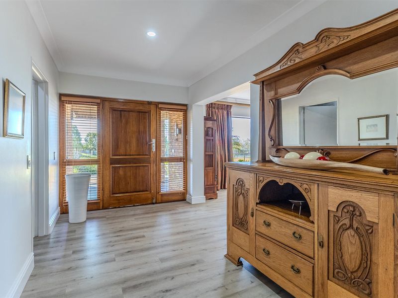 Welcoming entrance hall featuring a solid timber front door with side panels, modern laminate flooring, and recessed downlighting.