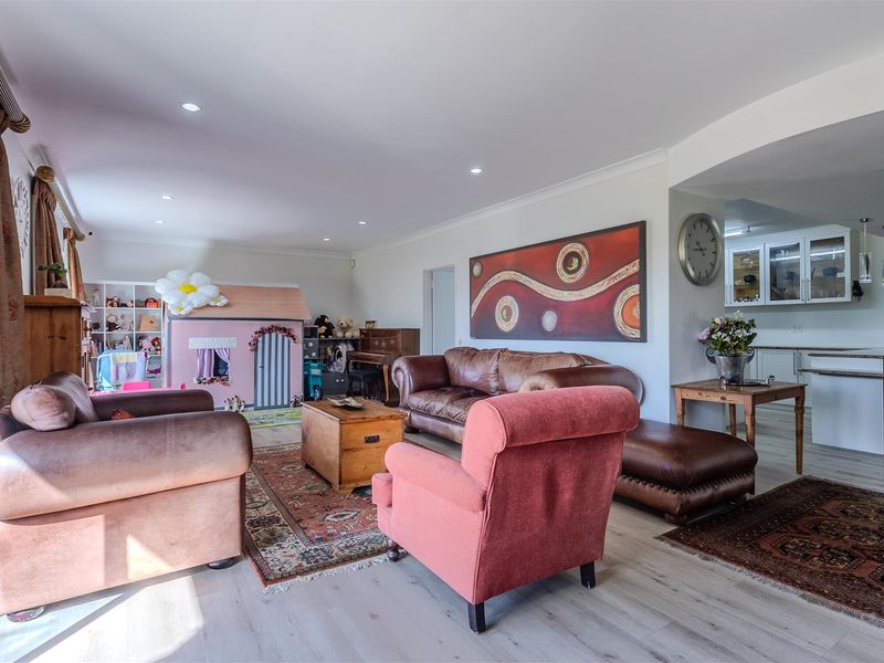 Spacious open-plan living area featuring modern laminate flooring, recessed lighting, and a seamless transition into a well-appointed kitchen with stone countertops.