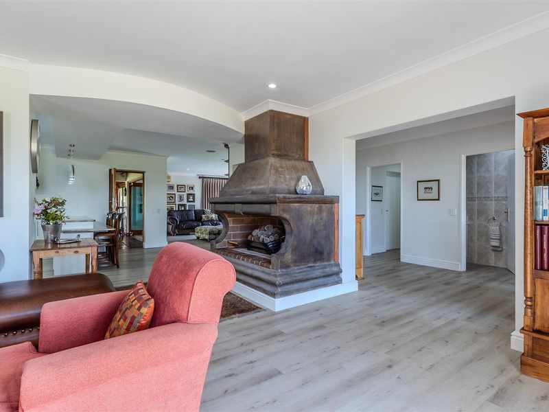 Spacious open-plan living area featuring a prominent central fireplace, modern laminate flooring, and neutral finishes, creating a warm and inviting atmosphere.