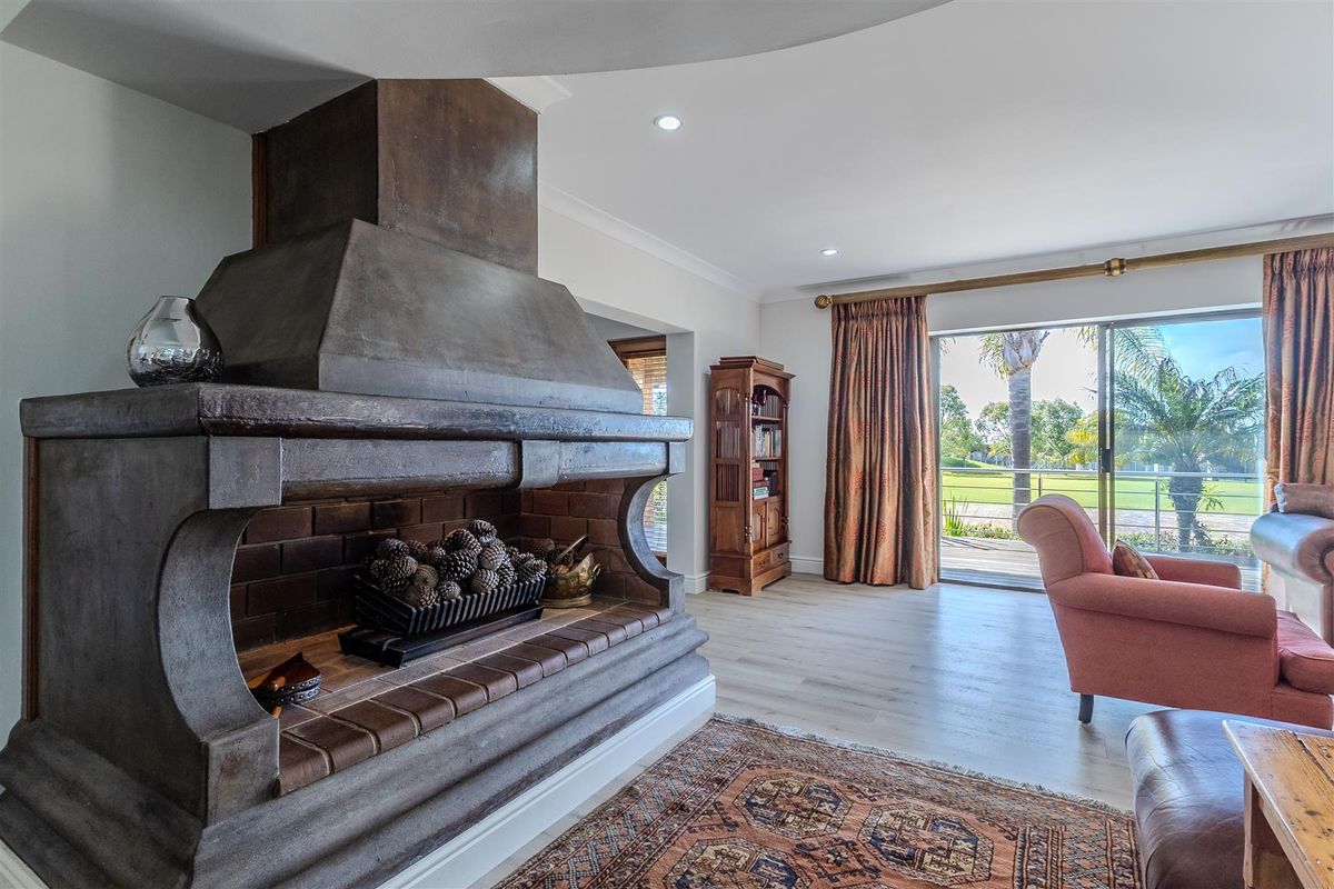 Spacious living room featuring a prominent masonry fireplace, modern laminate flooring, and large sliding doors providing direct access to the outdoor patio area.