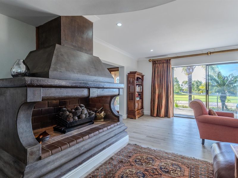 Spacious living room featuring a prominent masonry fireplace, modern laminate flooring, and large sliding doors providing direct access to the outdoor patio area.
