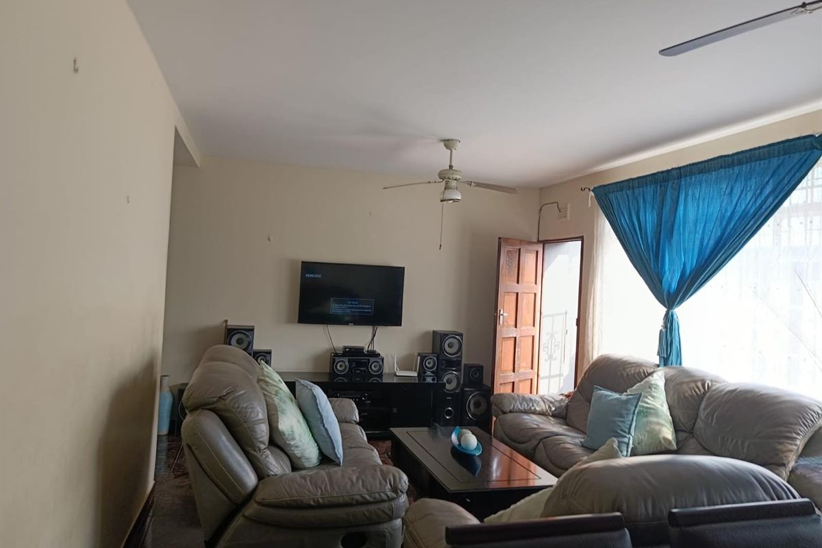 A comfortable living room featuring a ceiling fan, tiled flooring, and direct access to an outdoor area through a wooden door.