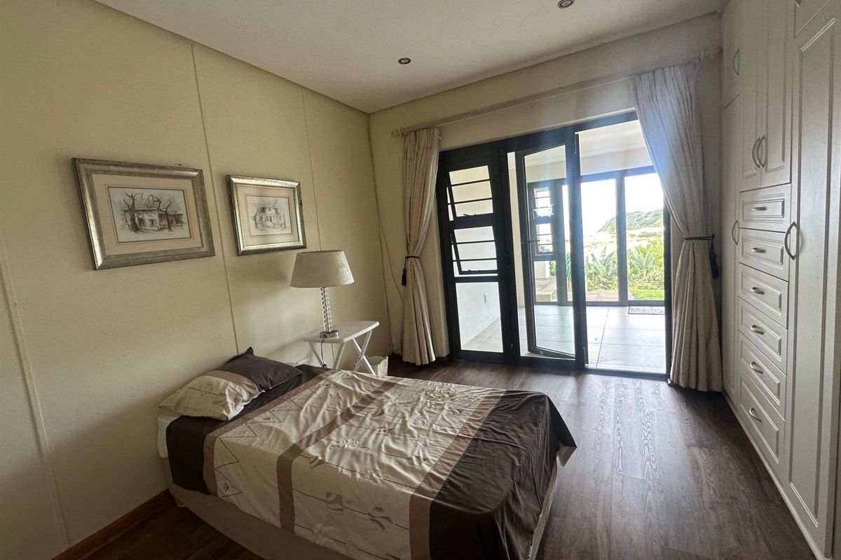 A well-lit bedroom featuring dark wood-look flooring, built-in cabinetry, and sliding glass doors that open onto an outdoor patio area.