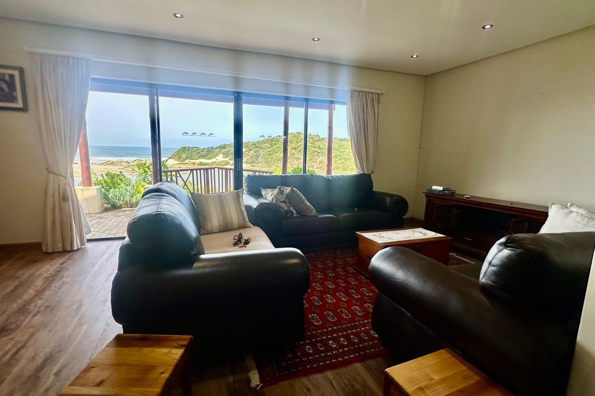 Spacious living room featuring large sliding glass doors that provide abundant natural light and direct access to a scenic coastal view.