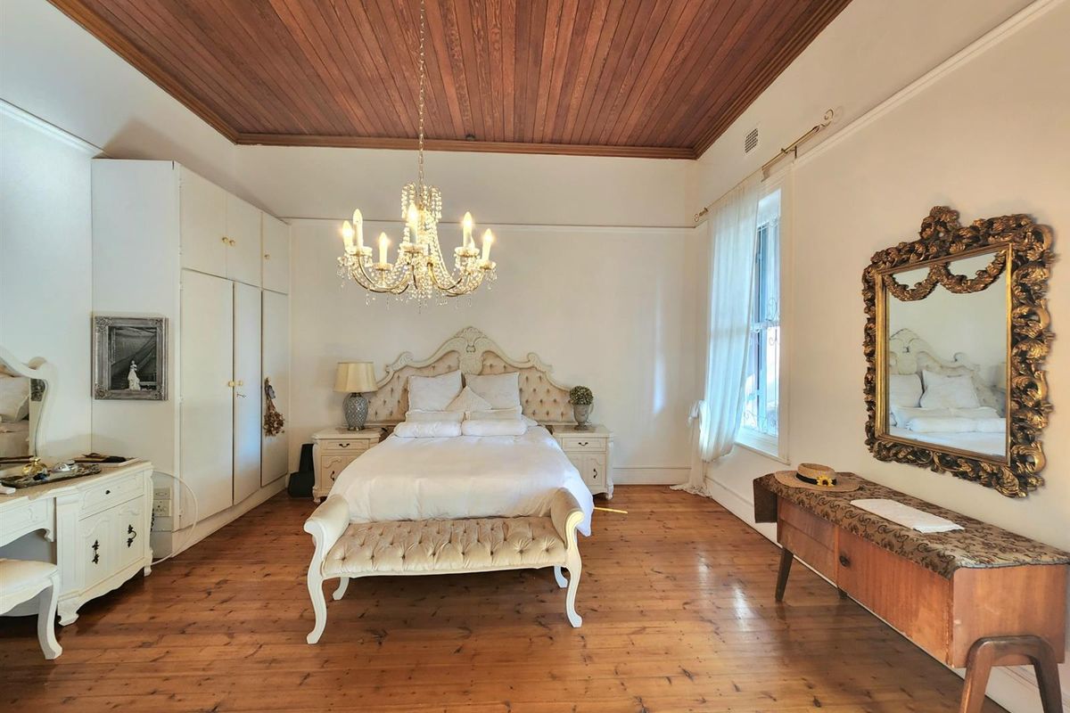 Spacious bedroom featuring polished timber flooring, a classic timber-paneled ceiling, and built-in wardrobe storage.
