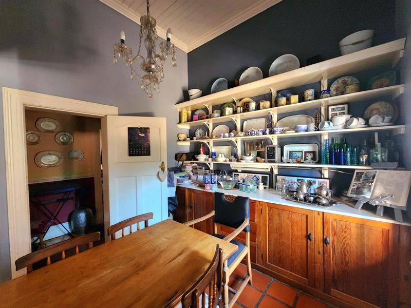 Dining room featuring built-in wooden cabinetry, open shelving, terracotta floor tiles, and a classic chandelier, offering a warm and traditional aesthetic.