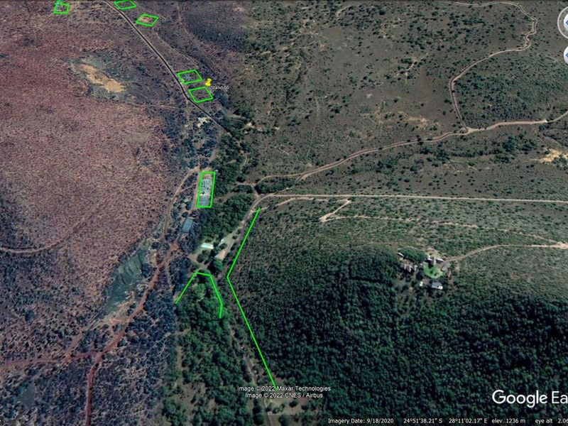 An aerial satellite view of the residential land plot, showing the surrounding natural landscape, terrain, and access roads.