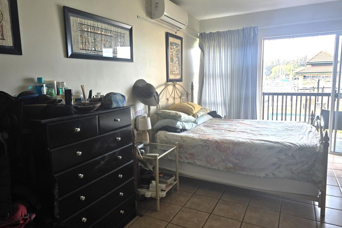 A bedroom featuring tiled flooring, a wall-mounted air conditioning unit, and sliding glass doors providing access to a balcony.