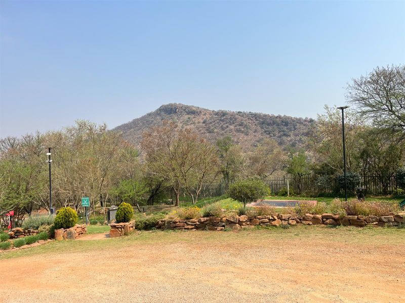 A scenic view of the surrounding landscape and mountain range from the residential property, featuring established garden beds and stone retaining walls.