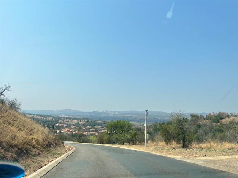 A scenic view of the surrounding landscape and residential neighborhood from the paved access road of the vacant land property.