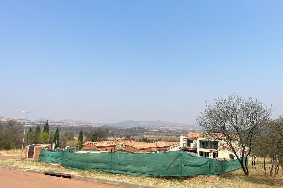 A view of a residential development site featuring ongoing construction, surrounded by natural landscape and distant mountain views.