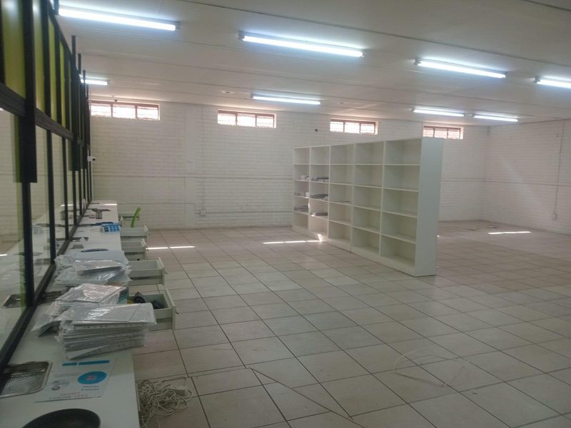Spacious commercial office area featuring tiled flooring, built-in shelving, and partitioned glass walls, suitable for a professional workspace or retail environment.