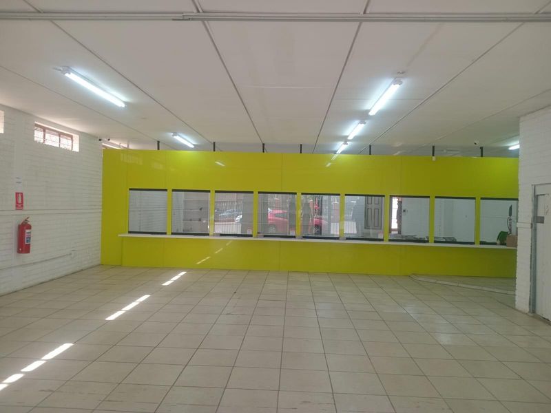 Open-plan commercial office space featuring a service counter, tiled flooring, and suspended ceiling, suitable for retail or administrative use.